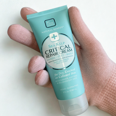 Hand holding a tube of Sea Kelp Critical Repair Cream on a white background
