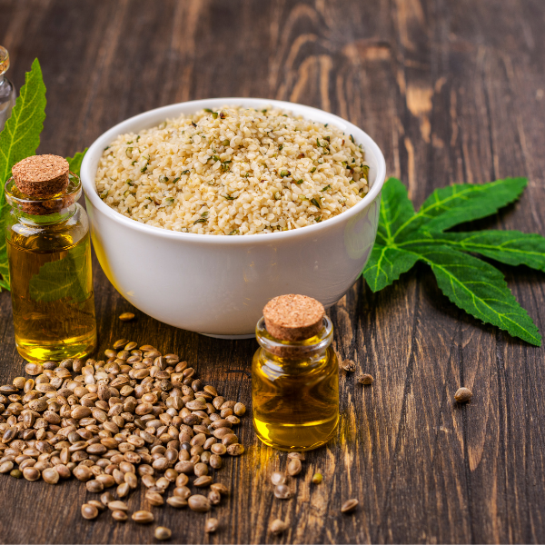 Cannabis seeds, oil, and ground cannabis in a bowl on a wooden surface
