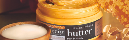 Jar of milk and honey butter with a wooden bowl of white powder and honeycomb in the background.