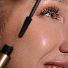 Close-up of a person applying Eco by Sonya Driver Mitzi Mascara to their eyelashes.