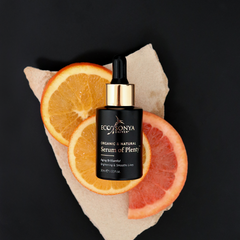 Eco Tan Sonya serum bottle with sliced oranges on a black background