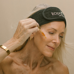 Woman applying skincare product with a applicator, wearing an Eco by Sonya headband.