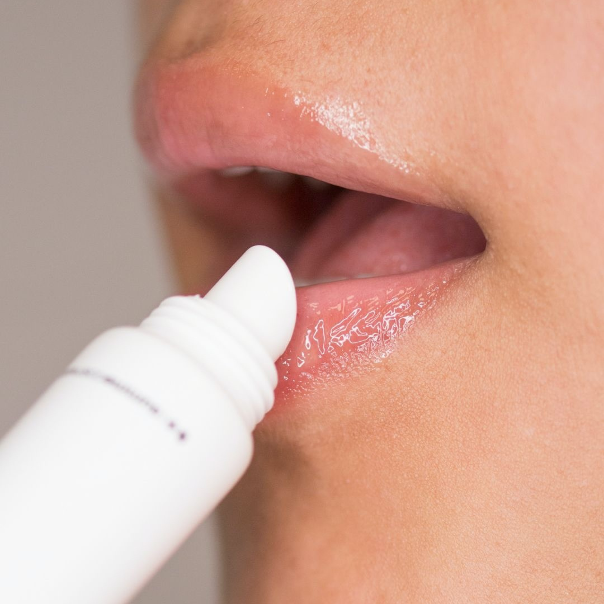 Person applying lip balm to their lips with a close-up view.