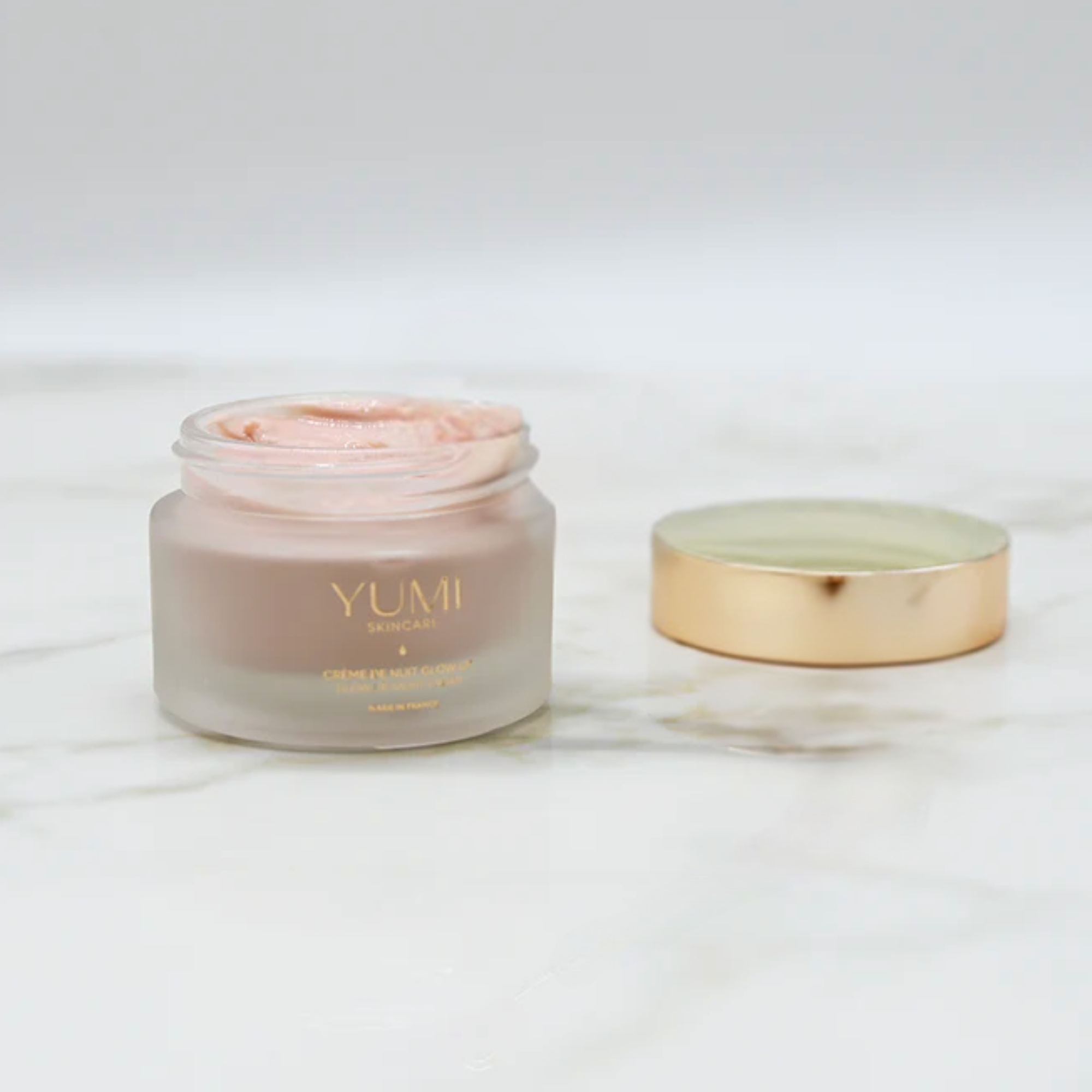 YUMI skincare jar with pink cream on a white background