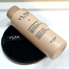 YUMI skincare bottle and black applicator on a white background